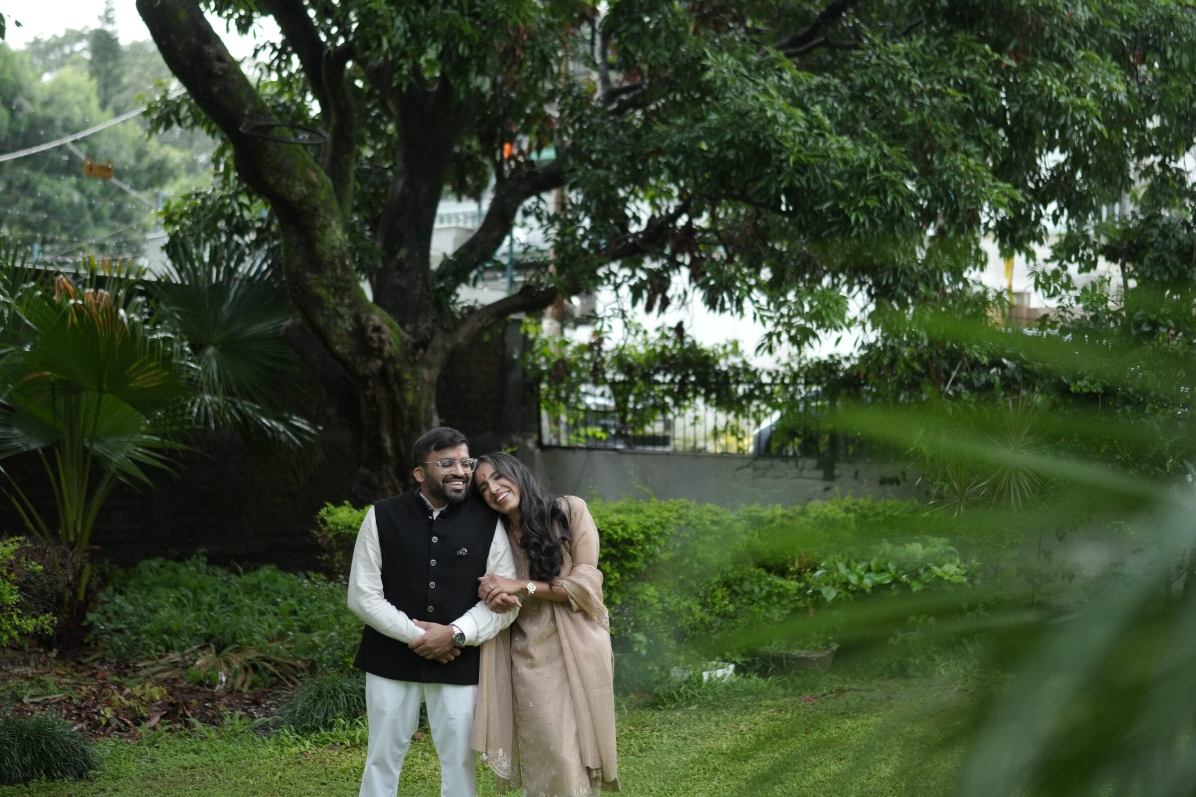 Sana and Gaurav standing together beneath a mango tree in a Dehradun garden.